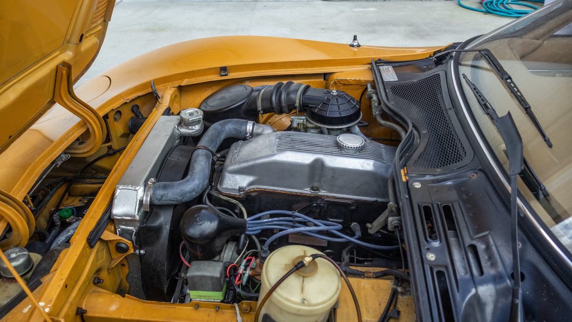 side view of engine bay with visible valve cover, hoses, radiator, wiring.